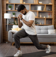 Indian male athlete in sport outfit doing sit ups on yoga mat during regular training at home. Modern interior of living room on background. Healthy lifestyle concept.